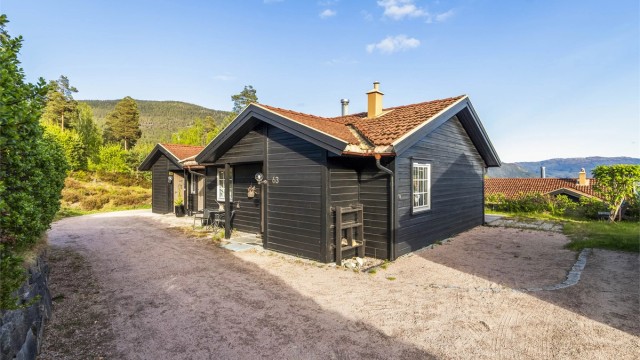 Parkering langs hytteveggen. Adkomst til hytta via overbygd inngangsparti.