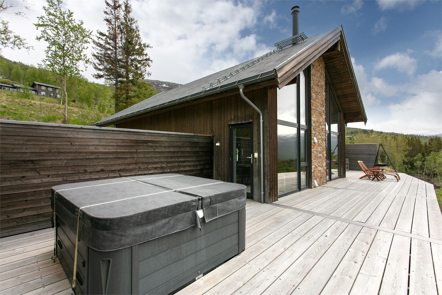 Stor, sørvendt terrasse med jacuzzi og flott utsikt over dalen og omkringliggende fjelltopper.
