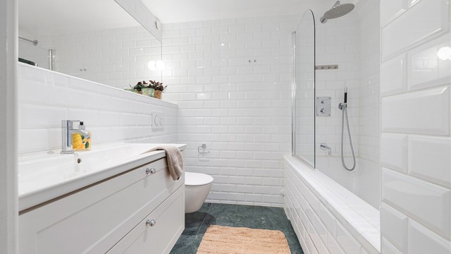 Baderommet er utstyrt med vegghengt servantinnredning med ovenpåliggende servant, vegghengt toalett og badekar med dusjløsning. Downlights i himling og mekanisk avtrekk gir god funksjonalitet og komfort.