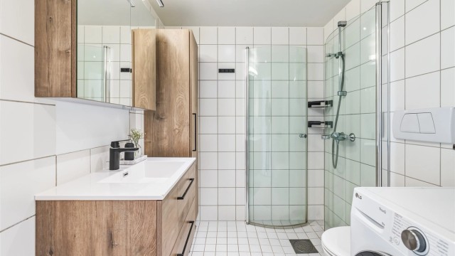 Prefabrikkert baderom fra byggeår med fliser på vegger og gulv. Det er varme i gulvet for en behagelig start på dagen.