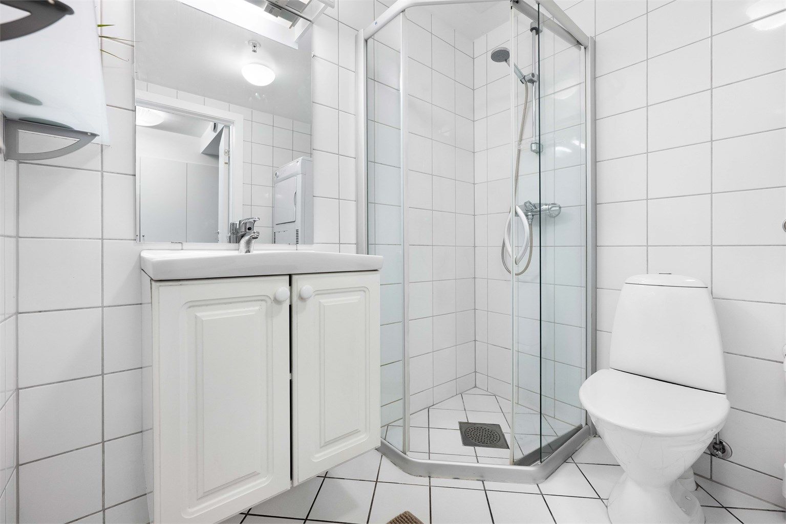 Dusjhjørne med buede glassdører og gulvstående toalett.