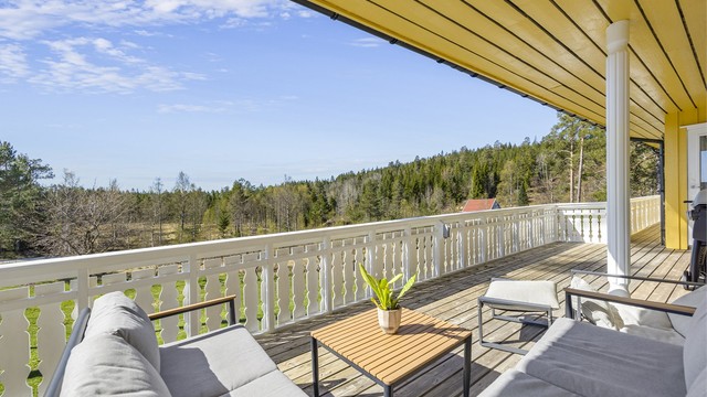 Fra verandaen har man en åpen og fin utsikt over hagen og de omkringliggende skogsområdene.