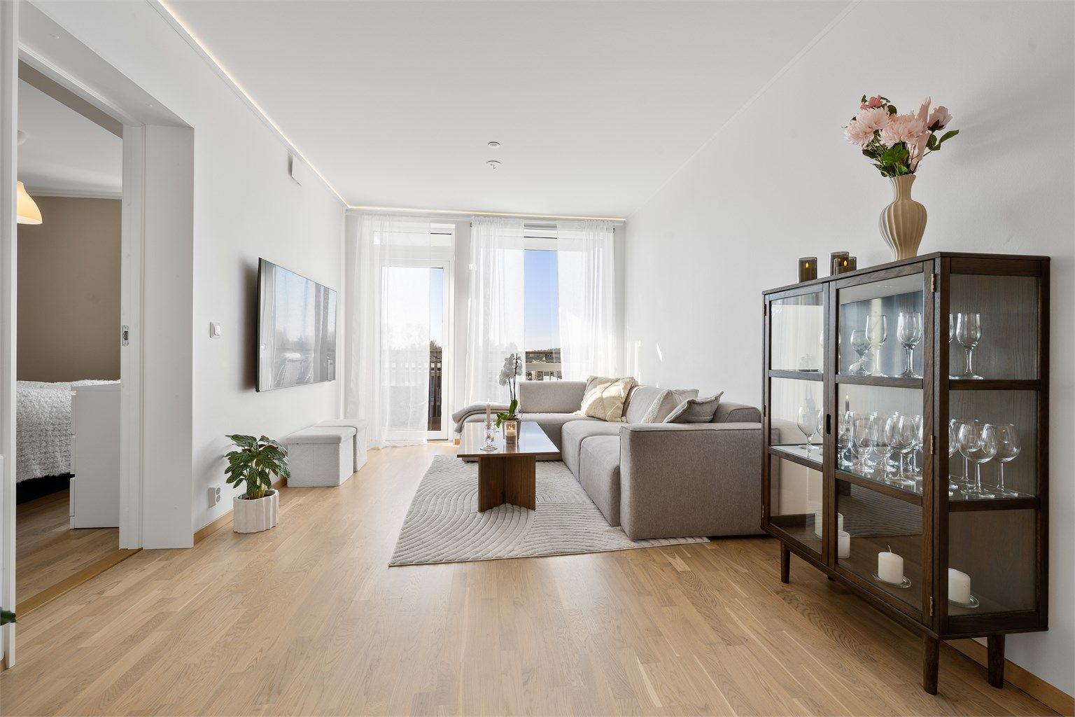 Lys stue med mye naturlig lys fra store vindusflater.