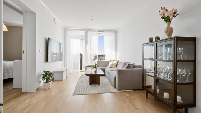 Lys stue med mye naturlig lys fra store vindusflater.