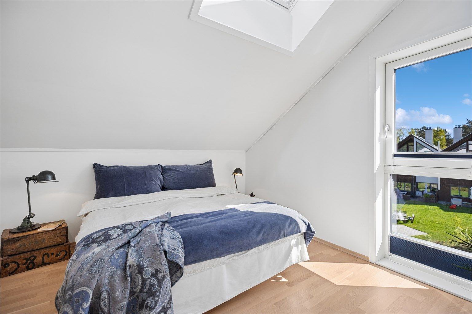 Boligens andre soverom fremstår lyst og innbydende, med store vinduer som slipper inn rikelig med naturlig lys. Takvinduet bidrar ytterligere til godt lysinnslipp og en behagelig romfølelse gjennom hele dagen. 