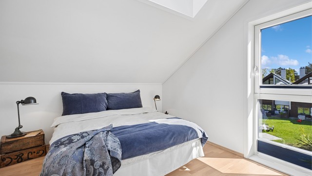 Boligens andre soverom fremstår lyst og innbydende, med store vinduer som slipper inn rikelig med naturlig lys. Takvinduet bidrar ytterligere til godt lysinnslipp og en behagelig romfølelse gjennom hele dagen.