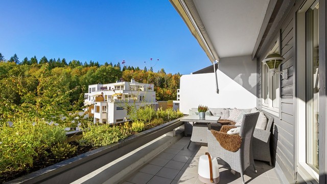 Vestvendt balkong med blomsterkasse og god plass til sittegruppe.