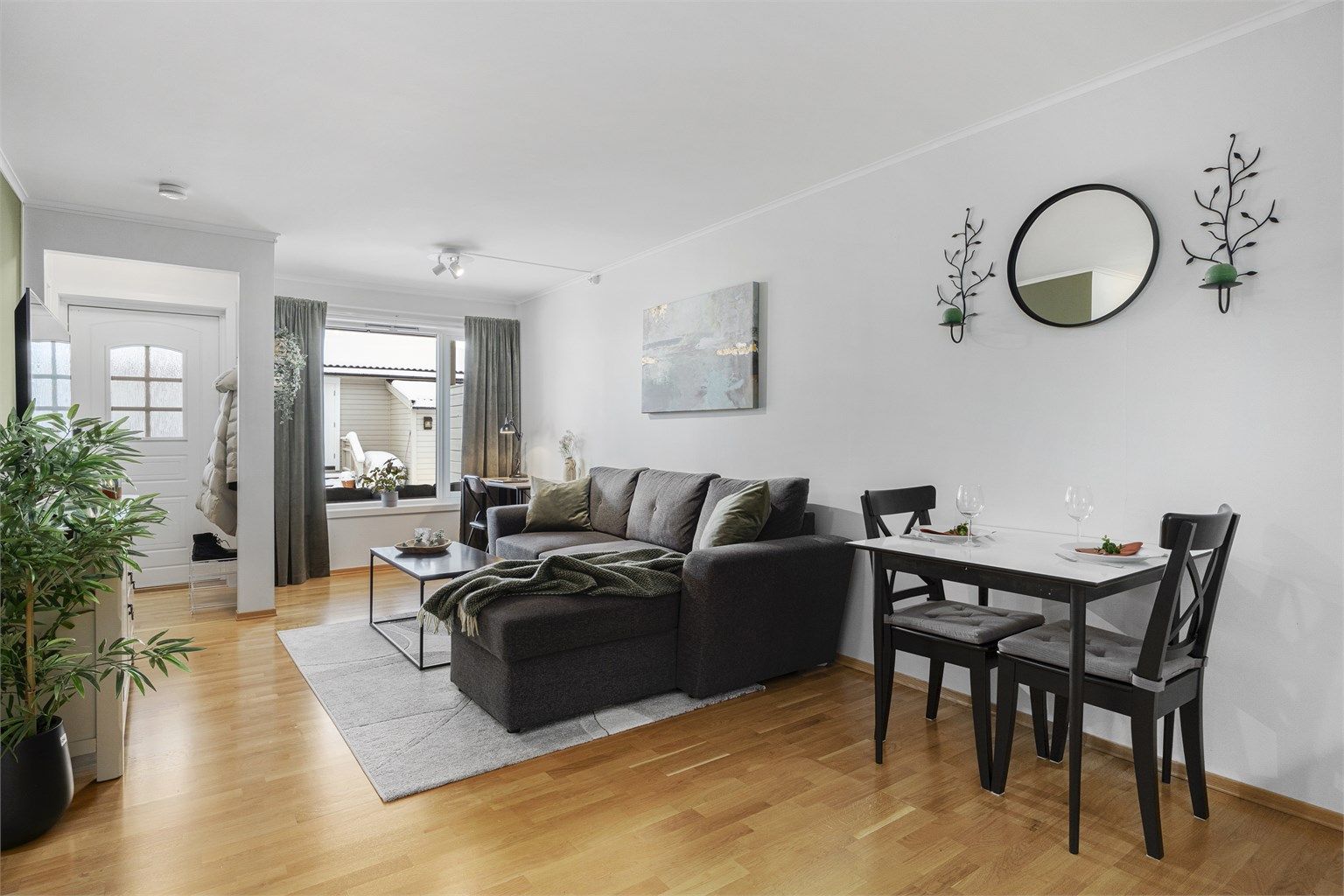 Lys stue med god plass til sofagruppe, spisestue og tilhørende møblement.