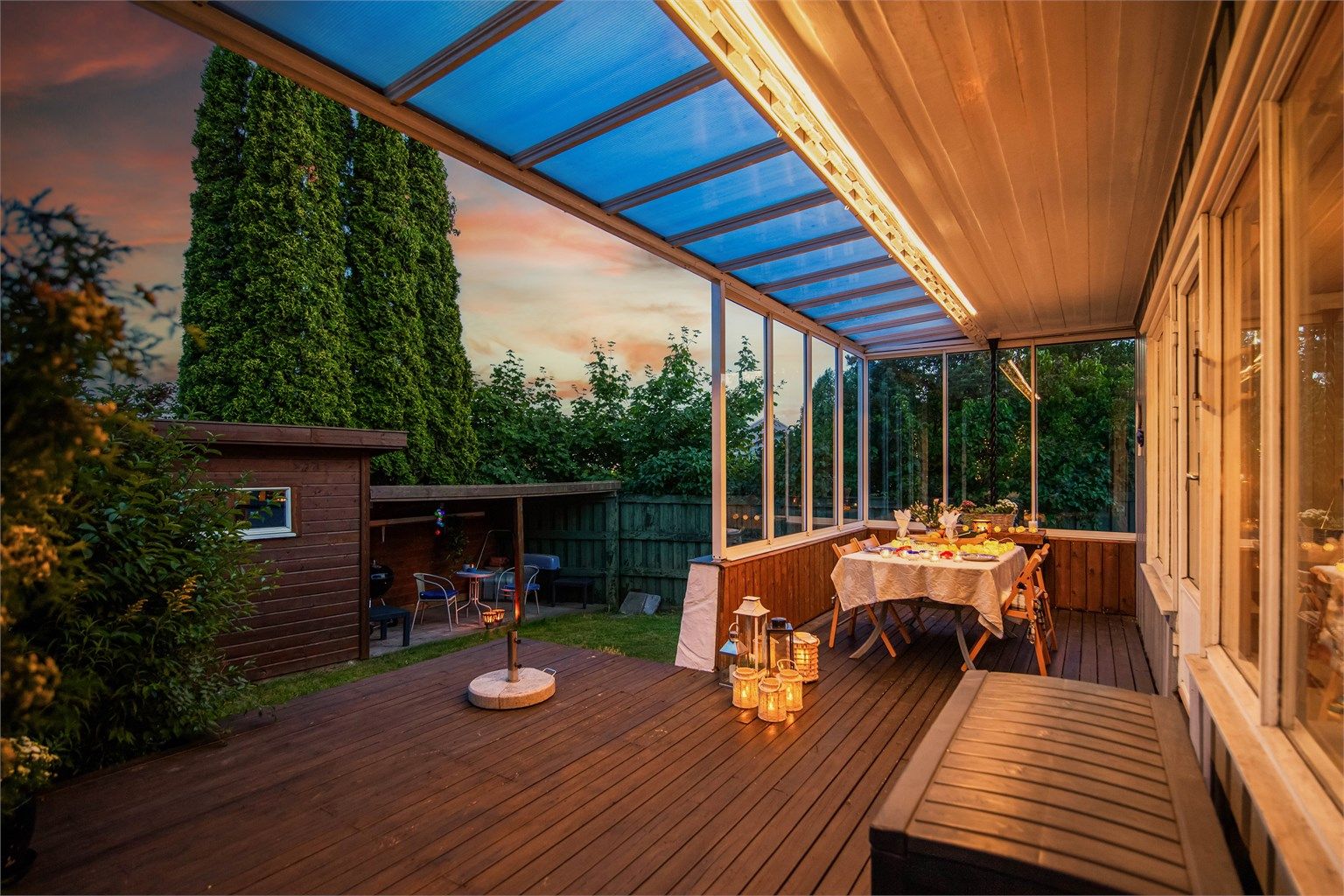 En del av uteplassen er innglasset, slik at du kan sitte lunt og skjermet – perfekt for å nyte lange sommerkvelder, uansett vær og vind.
