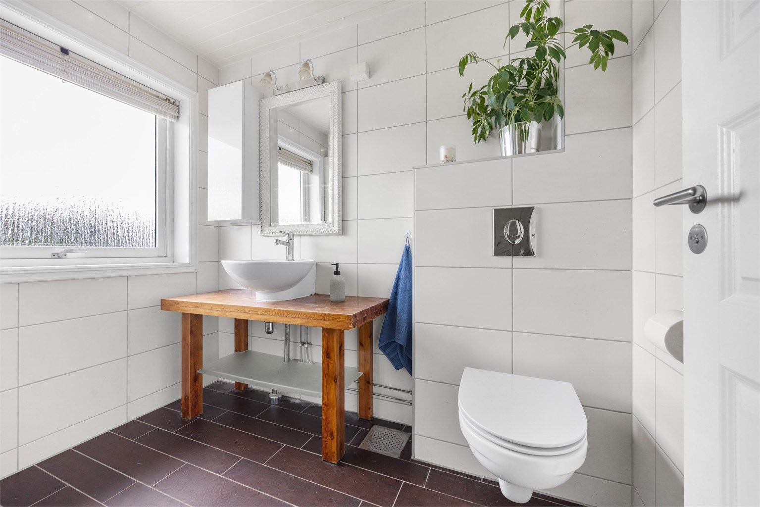 Baderommet har servantmontering på trebenk og vegghengt toalett.