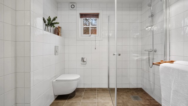 Rommet har et vegghengt toalett og et romslig dusjhjørne med svingbare glassdører.