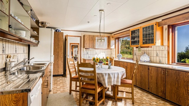 Kjøkkenet er så romslig at hele familien kan bli med å lage mat! Innredningen omkranser spiseplassen, en naturlig samlingsplass i rommet. Mellom benk og overskap er det keramiske flis.