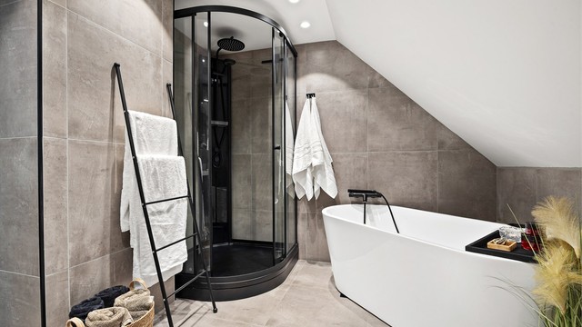 Badet er innredet med både dusjkabinett som har regnfallsdusj og badekar med veggmontert hånddusj.