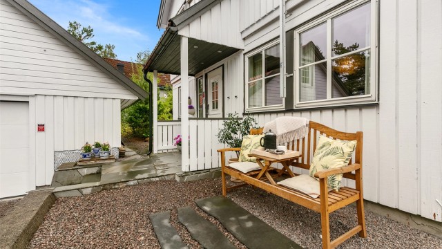 Et lunt og sjarmerende inngangsparti med sittebenk og grønne omgivelser.