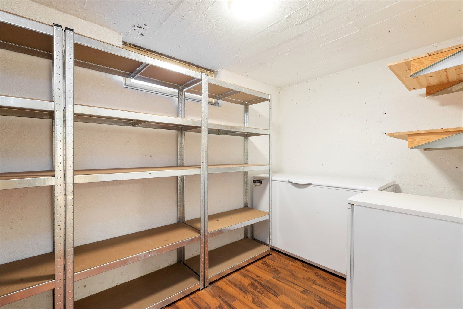 Bod i kjelleren er i dag innredet med oppbevaringshyller og plass til fryser.