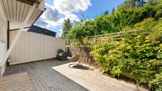 Skjermet uteplass med forstøtningsmur av betongblokker.