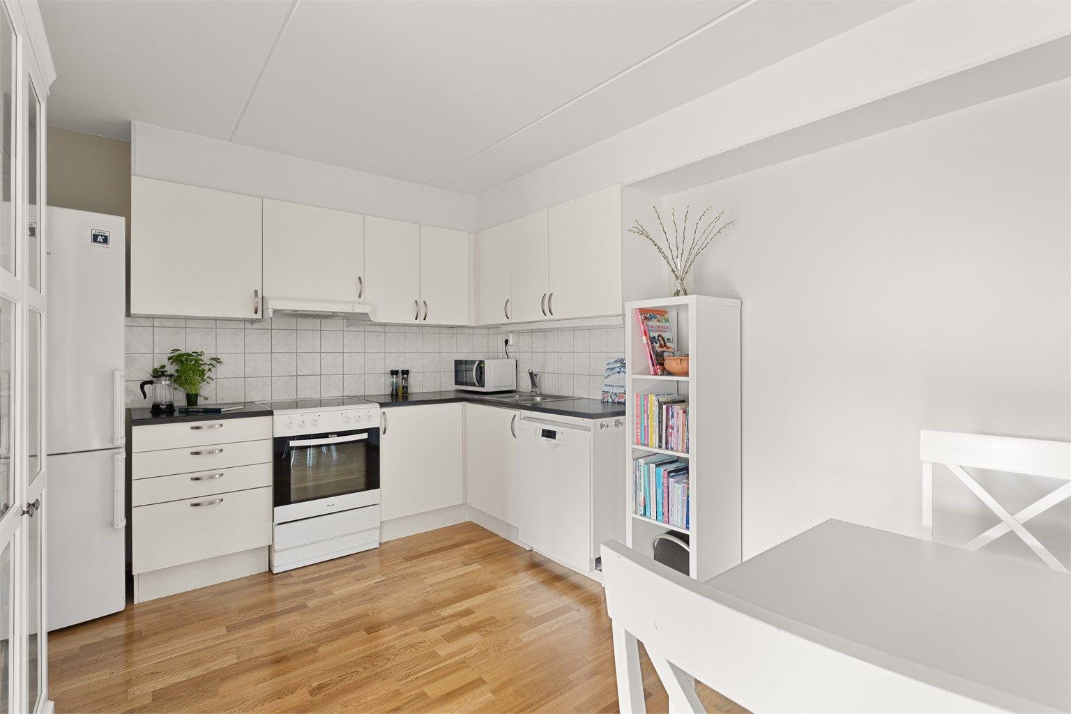 Kjøkkeninnredningen med hvite, glatte fronter. God skap- og benkeplass for matlaging.