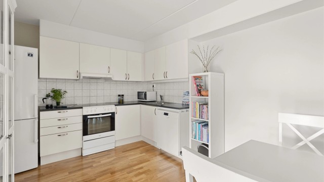 Kjøkkeninnredningen med hvite, glatte fronter. God skap- og benkeplass for matlaging.