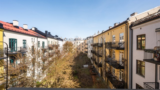 Utsikt fra balkongen mot den skjermede og grønne bakgården, et fellesareal som gir en rolig kontrast til det pulserende livet i Markveien.