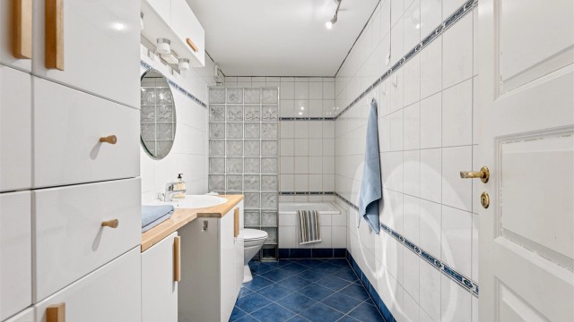 Hovedbadet er flislagt og utstyrt med badekar, servantinnredning og varmekabler i gulvet.