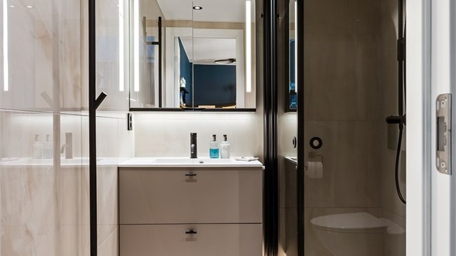 Badet ved soverommet har også en delikat utførelse med store flisoverflater og sorte detaljer.