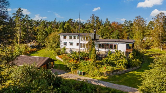 Huset er omsvøpet av vakre grønne trær og busker i rolige omgivelser.