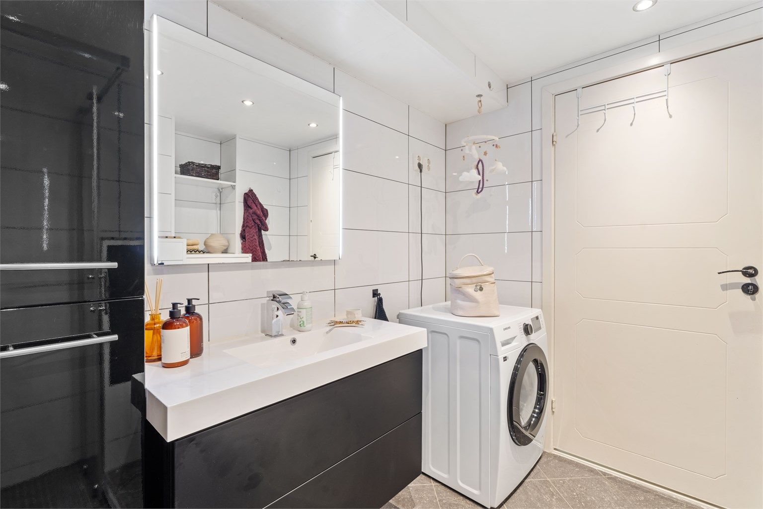 Her er det vegghengt toalett, servantinnredning og praktisk opplegg for vaskemaskin.