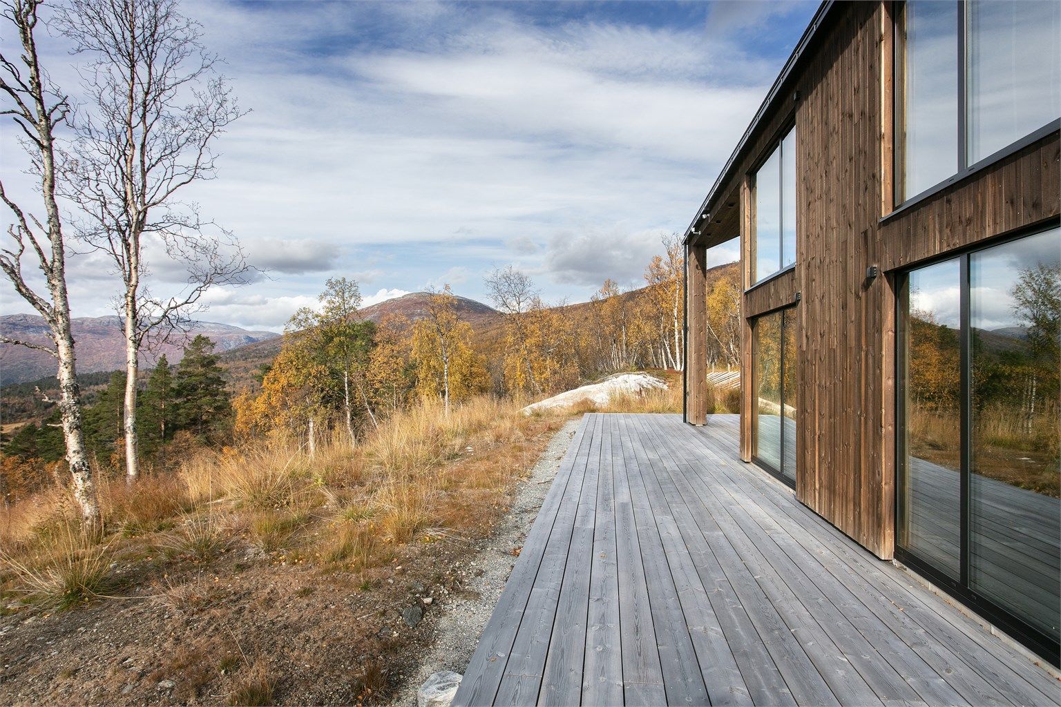 Åpent utsyn mot fjellene og omkringliggende natur fra terrasseplattingen.