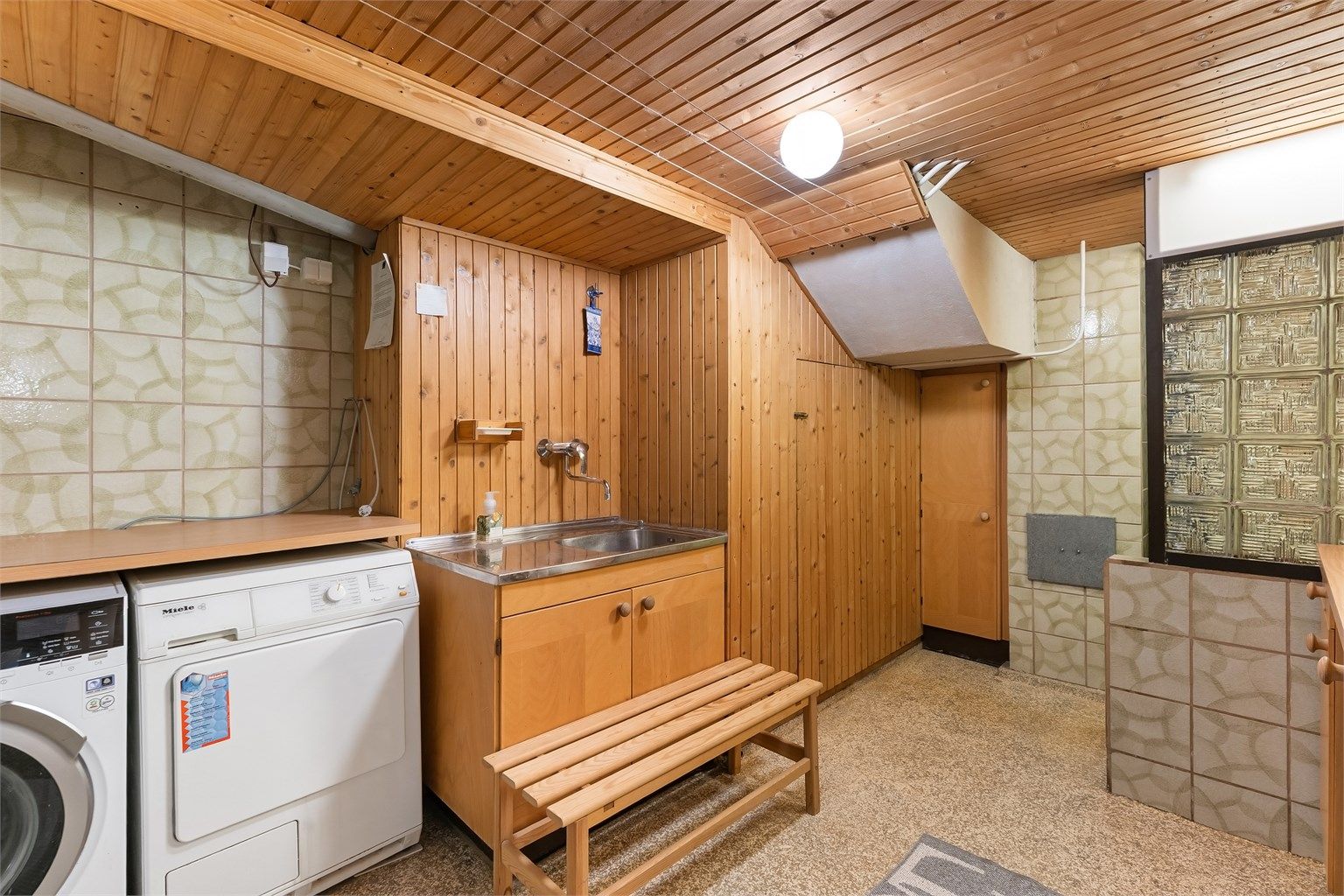 Stort vaskerom i kjelleren med opplegg for vaskemaskin og tørketrommel, samt en dusjsone.