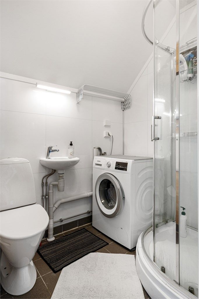 Badet har flislagt gulv med varme og baderomsplater på vegg samt opplegg for vaskemaskin. Videre er badet utstyrt med servant, toalett og dusjkabinett.