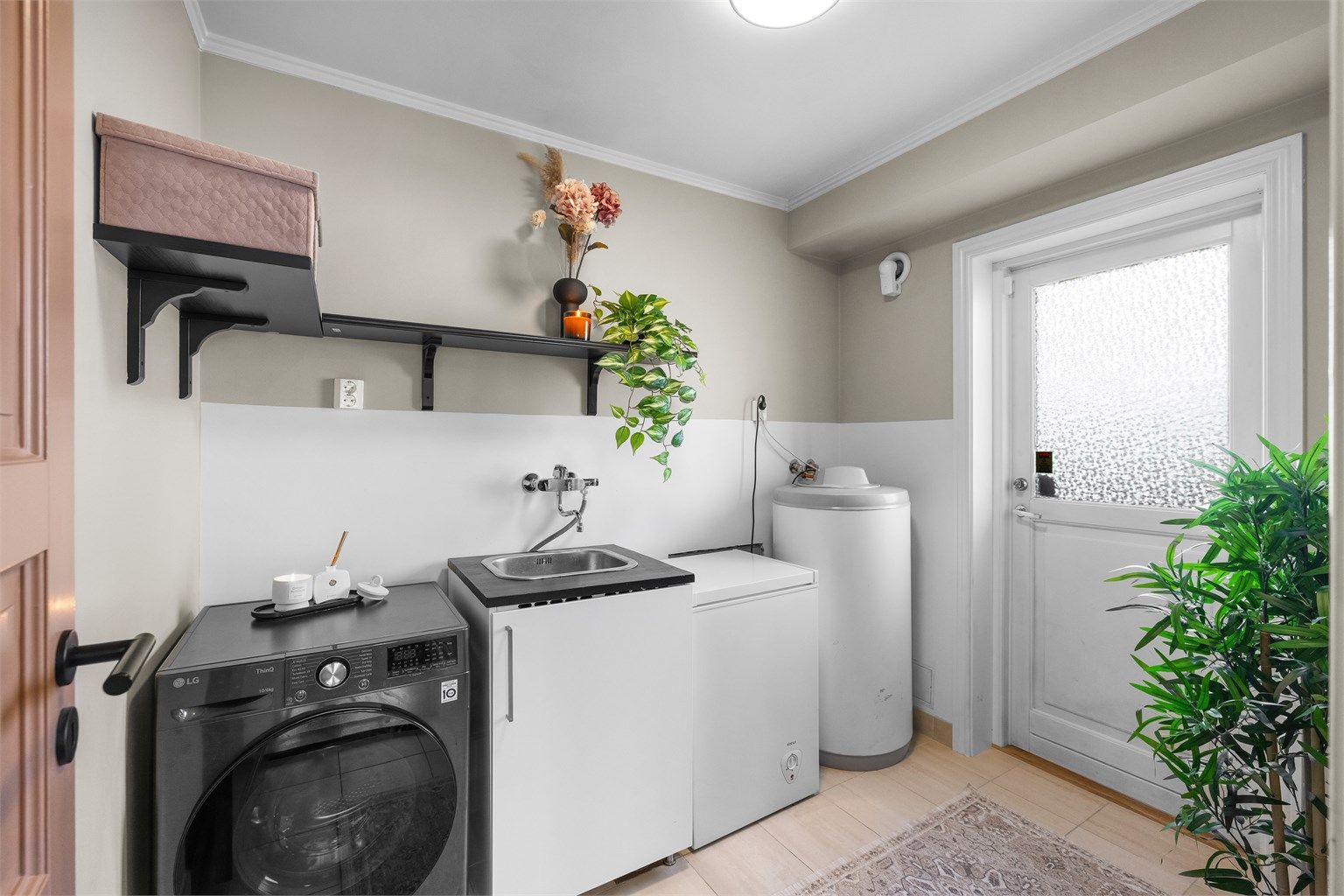 Praktisk vaskerom med flislagt gulv, gulvvarme og egen utgang til hagen.