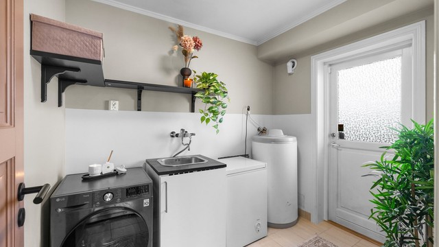 Praktisk vaskerom med flislagt gulv, gulvvarme og egen utgang til hagen.