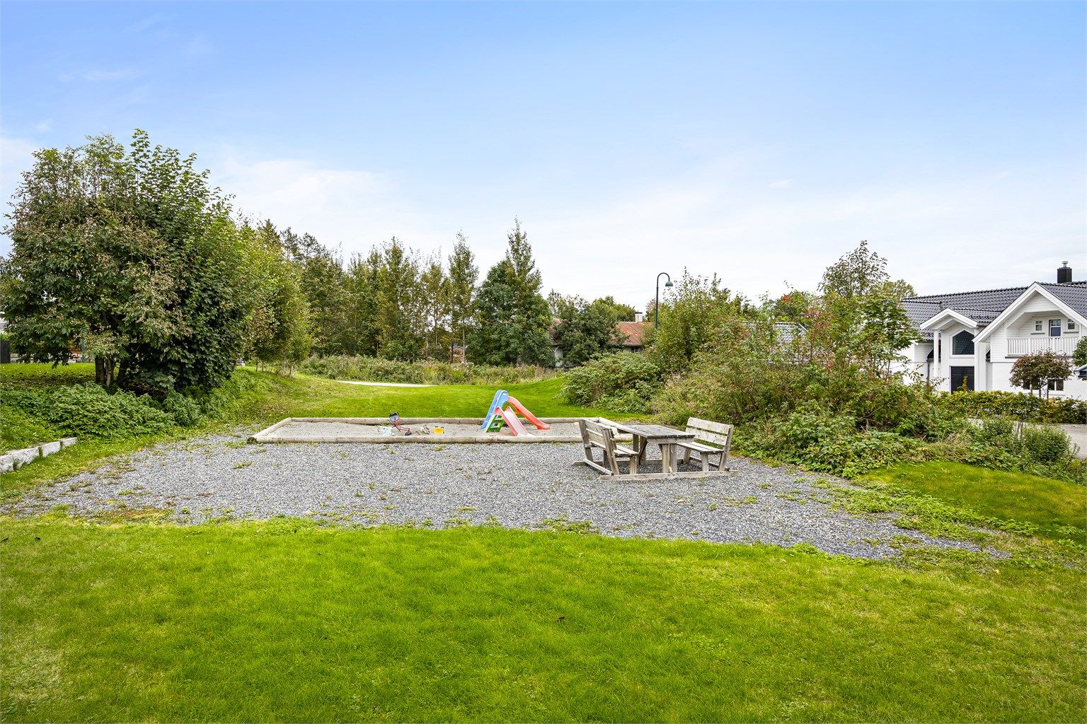 Et stort, felles grøntareal med lekeplass ligger rett i forkant av eiendommen.