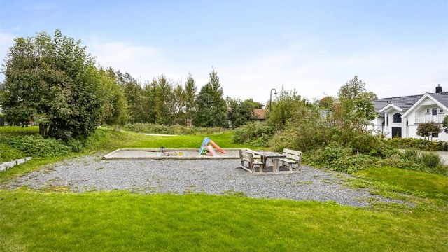 Et stort, felles grøntareal med lekeplass ligger rett i forkant av eiendommen.