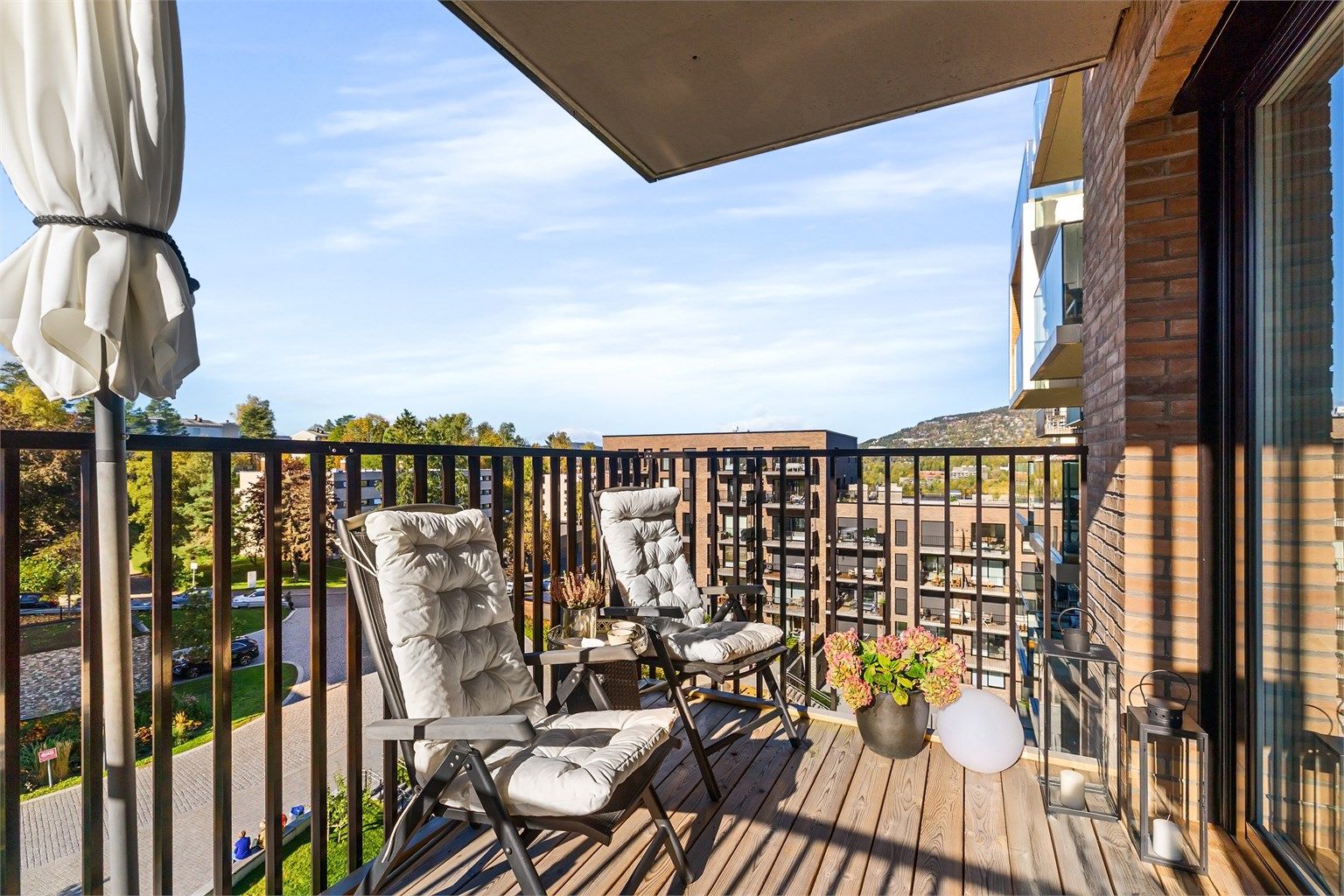 Balkongen har terrassebord, metallrekkverk og teglkledde yttervegger, samt utebelysning og stikkontakt.