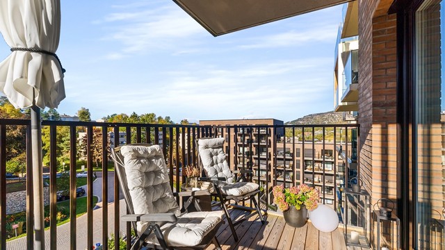 Balkongen har terrassebord, metallrekkverk og teglkledde yttervegger, samt utebelysning og stikkontakt.