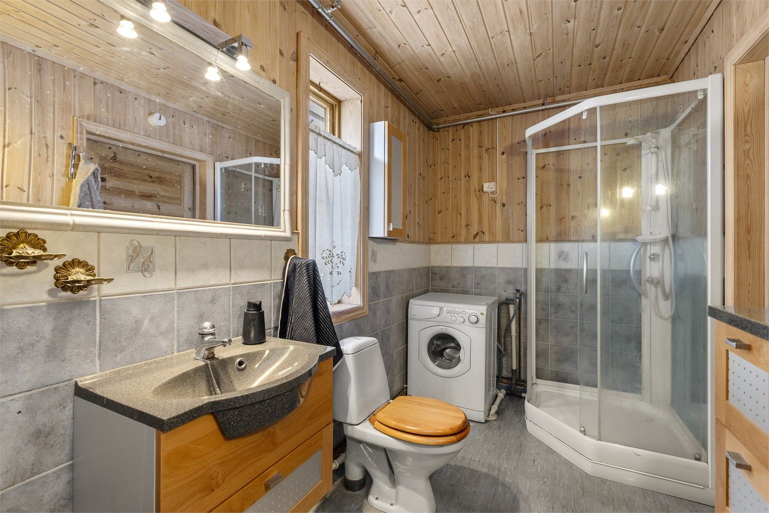 Koselig bad i 1. etasje med gulvbelegg, flislagte veggflater kombinert med panel og panel i himling. 