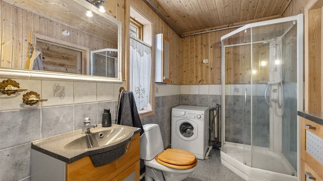 Koselig bad i 1. etasje med gulvbelegg, flislagte veggflater kombinert med panel og panel i himling.