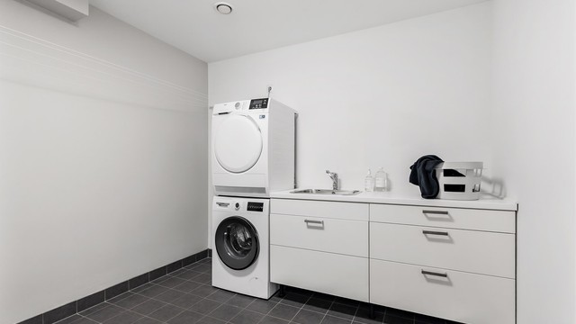 Vaskerom med flislagt gulv med varme og vegger i malte flater. Baderomsinnredning med slette fronter. Benkeplate av laminat. Nedfelt oppvaskkum av rustfritt stål med ett-greps. Mekanisk avtrekksventil på vegg. Opplegg for vaskemaskin/tørketrommel.