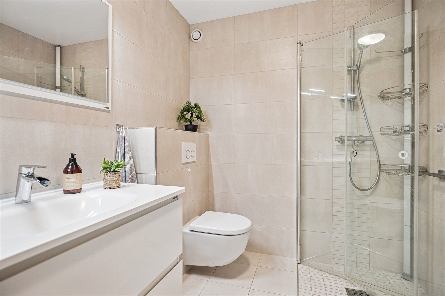 Lekkert, moderne og innbydende bad med stilren servantinnredning m. god oppbevaringsplass, vegghengt wc, og et romslig dusjhjørne med innfellbare glassdører. Materialvalg og løsninger er gjennomtenkte, og helheten gir et behagelig og luksuriøst preg. 