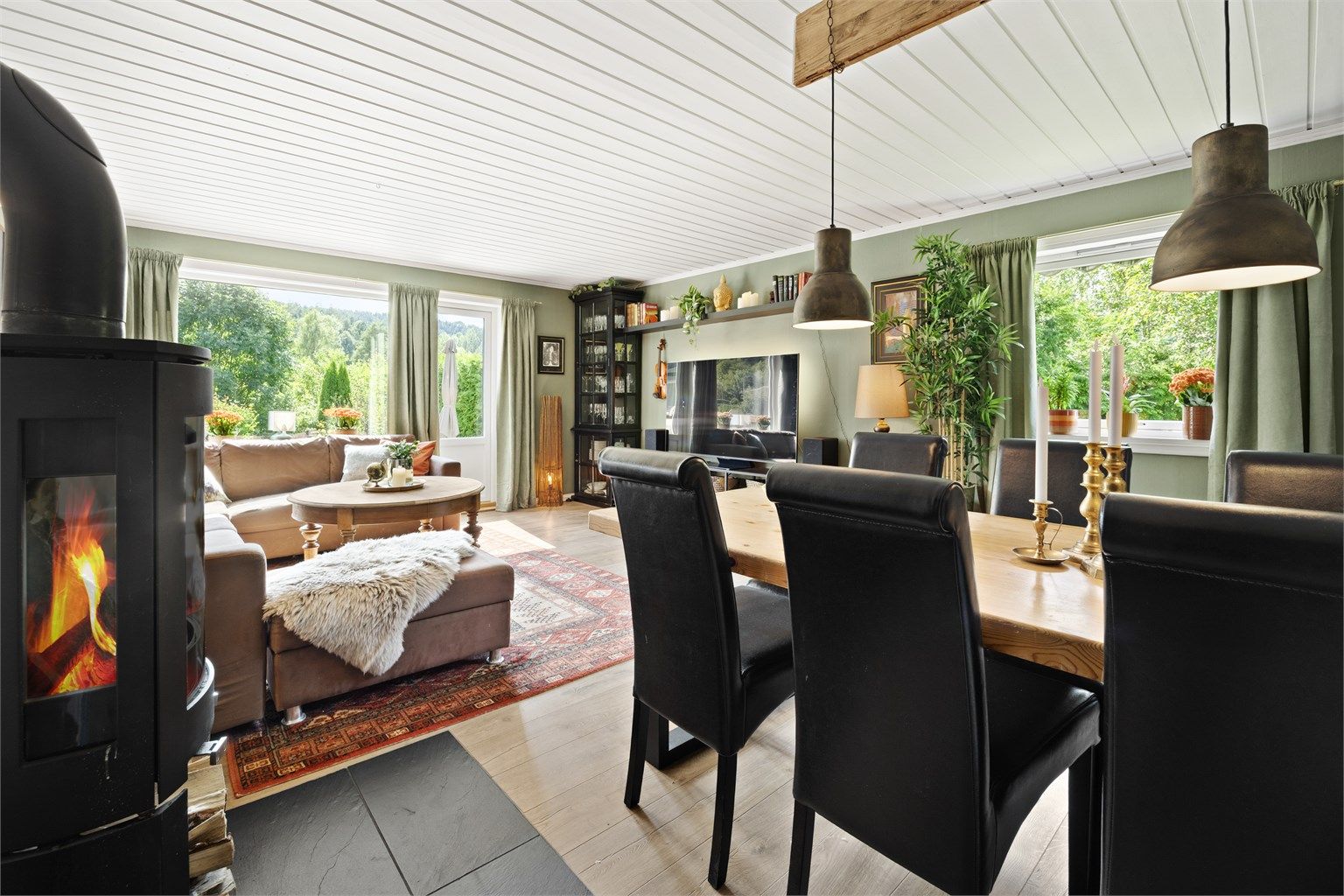 Stuen har plass til både spisebord og sofagruppe, og oppvarmes effektivt med peisovn.