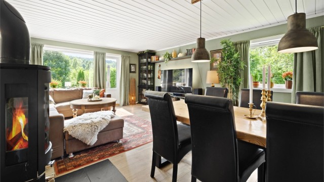 Stuen har plass til både spisebord og sofagruppe, og oppvarmes effektivt med peisovn.