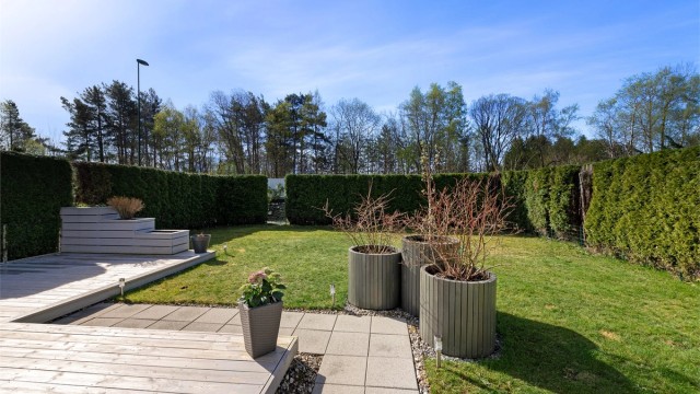 Terrassen går over i en flat og lettstelt hage, perfekt for lek og sosiale sammenkomster.