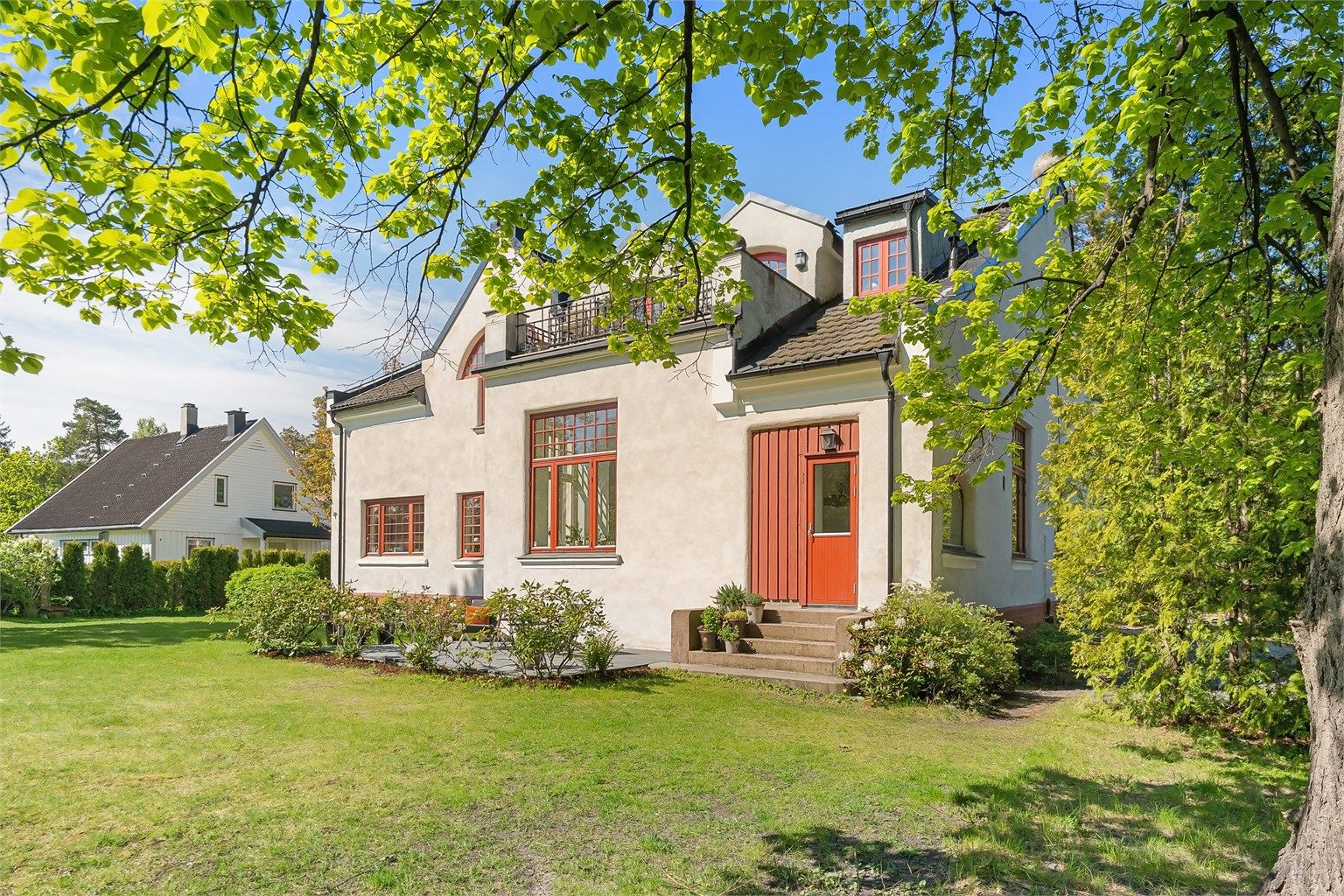 Eiendommen ligger i et ærverdig murbygg fra 1898, tilbaketrukket på en stor, grønn tomt.