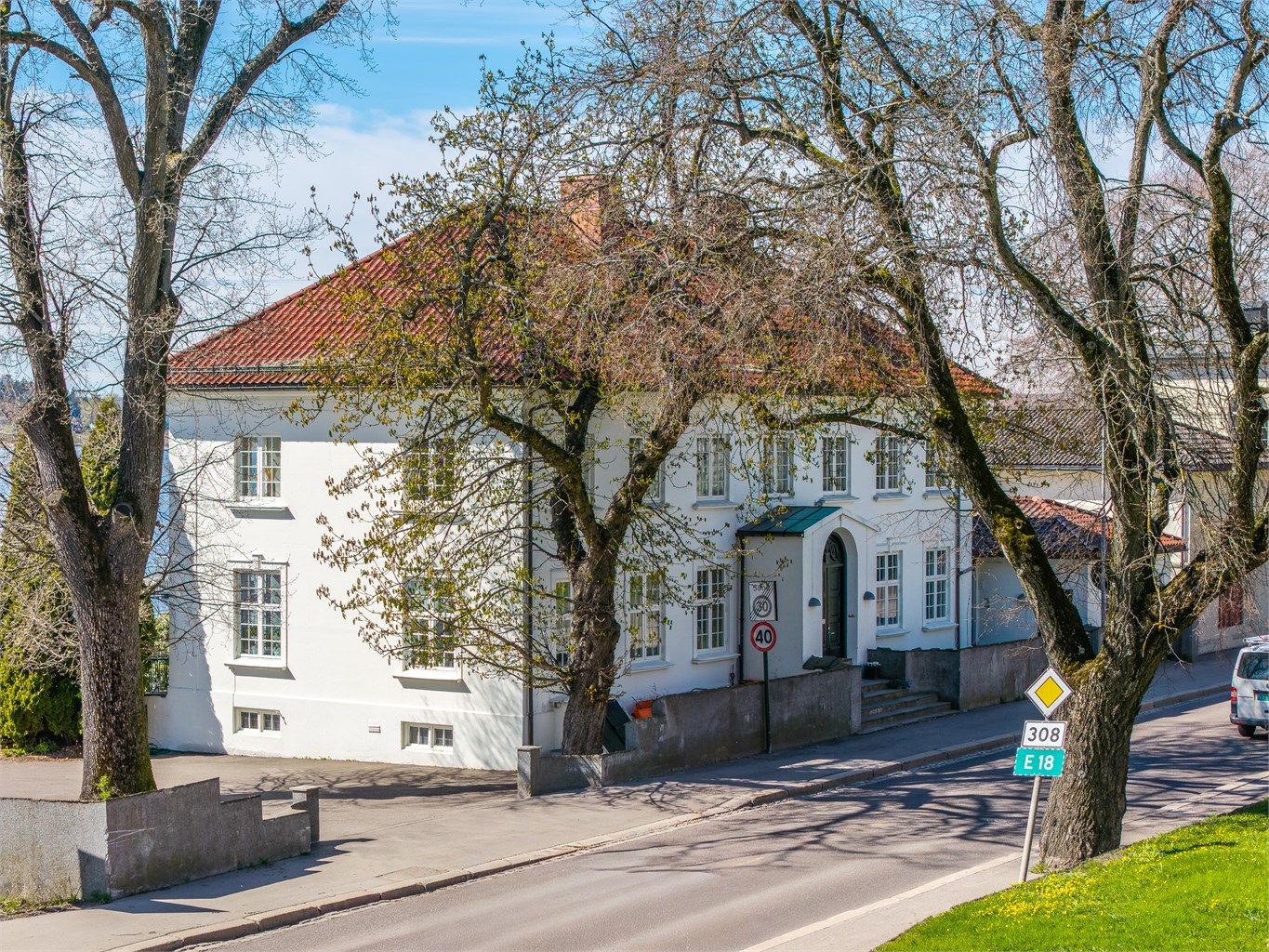 Eiendommen ligger markant til i landskapet, med pussede murfasader og glassert takstein.