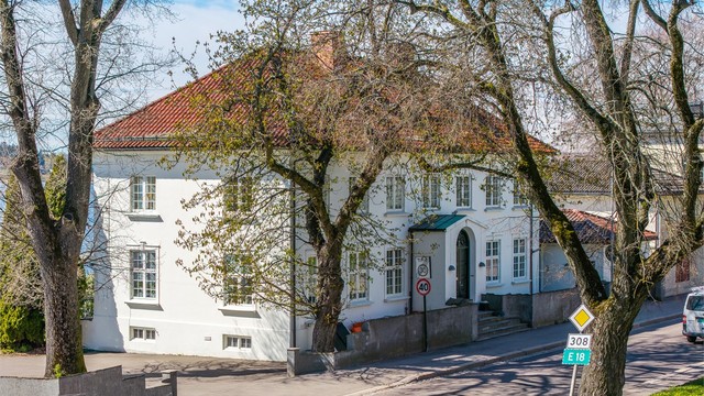 Eiendommen ligger markant til i landskapet, med pussede murfasader og glassert takstein.