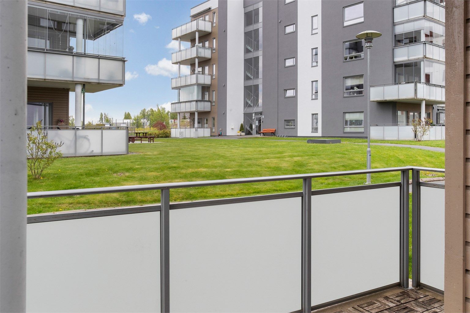 Fra uteplassen er det utsikt over sameiets fellesarealer med gressplen og beplantning.