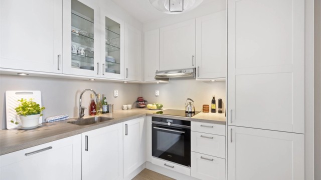 Åpen kjøkkenløsning mot stue. Flott Norema kjøkkeninnredning med profilerte fronter og benkeplate med laminert overflate. Integrerte hvitevarer som stekeovn med pyrolyse, platetopp, oppvaskmaskin og kjøleskap med fryser