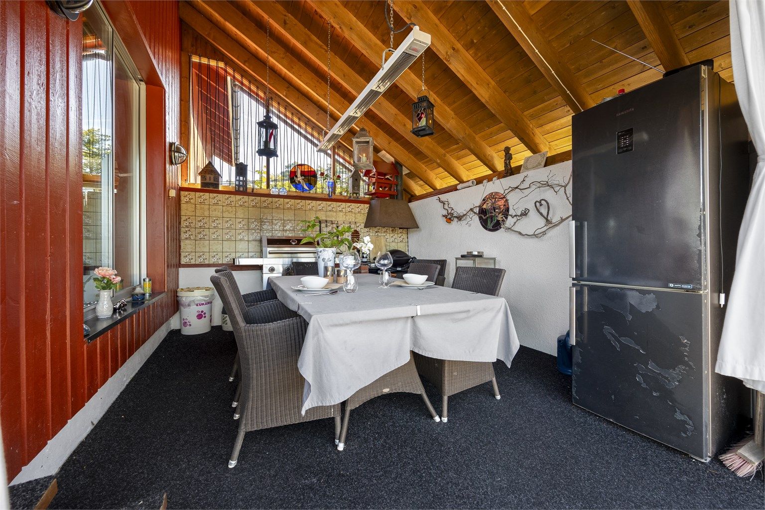 Overbygget uteplass med plass til spisebord og grill.