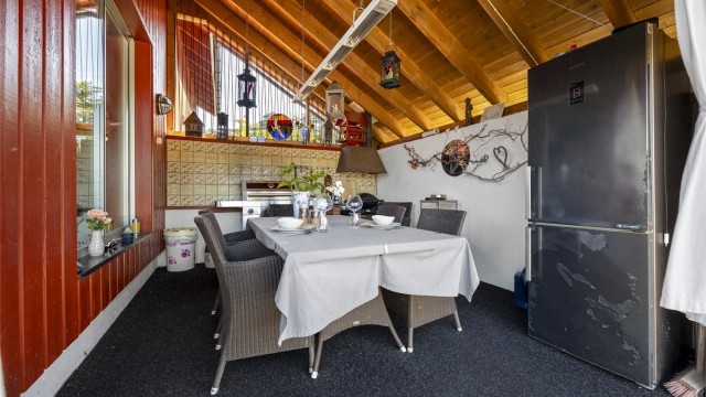 Overbygget uteplass med plass til spisebord og grill.